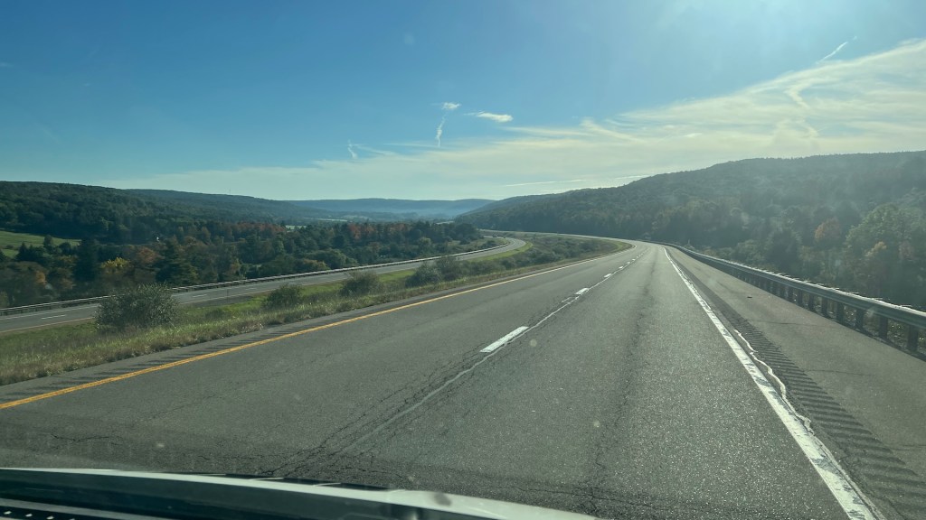 Open highway winding through hilly landscape under a clear blue sky.